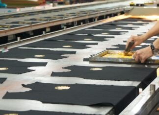 6 Cost-Effective Strategies To Promote Your T-Shirt Printing Business a person cutting fabric on a conveyor belt