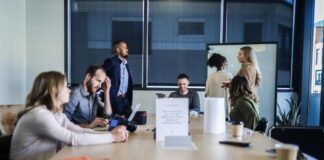 A team in a conference room, some sitting, some standing, discussing successful account planning.
