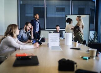 What Goes Into Account Planning A team in a conference room, some sitting, some standing, discussing successful account planning.