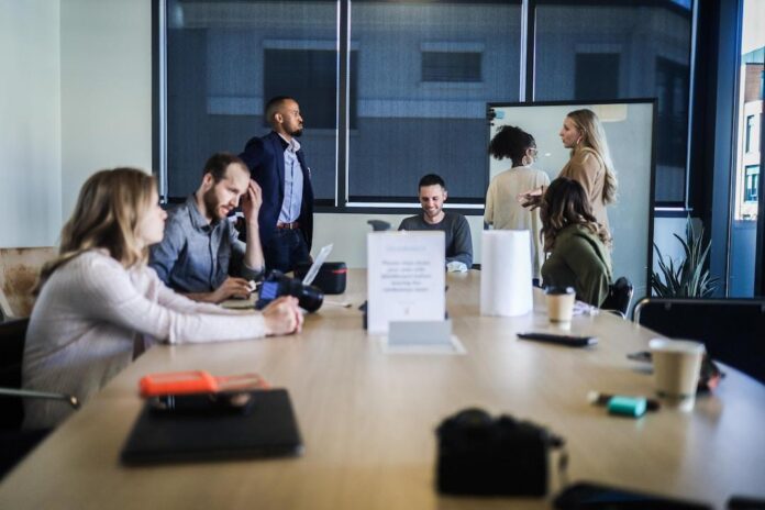 img A team in a conference room, some sitting, some standing, discussing successful account planning.