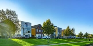 white and brown house near green grass field and body of water during daytime