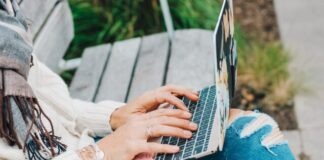 person in white long sleeve shirt and blue denim jeans using macbook pro