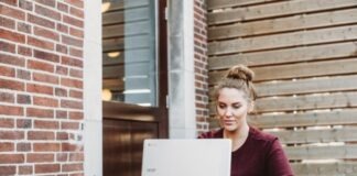 woman sitting and holding white Acer laptop near brown wooden wall