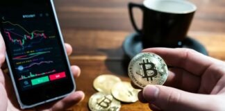 a person holding a bitcoin next to a cup of coffee