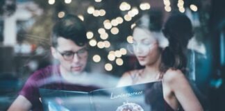 man sitting beside woman while reading