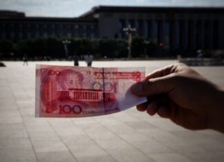 Strengthening China’s Global Financial Impact through the Digital Yuan a person holding a piece of paper with a picture of a building in the background