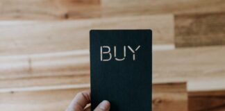 a person holding a black book with the word buy written on it