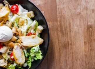 meat with vegetables and sliced tomatoes in black bowl