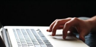 person using macbook pro on brown wooden table