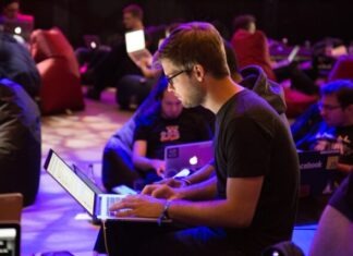 man using laptop in front of brown chair