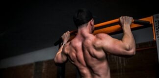 topless man in black shorts holding orange bar