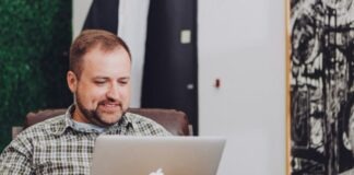 man smiling and using MacBook