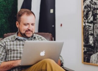 man smiling and using MacBook