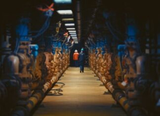Why is the Expertise of an Underground Pipe Supplier Essential in District Heating: Benefits a man standing in a large room with lots of pipes