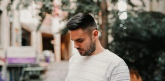 man in white and gray striped polo shirt holding black smartphone