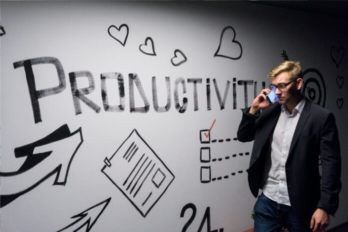 Photo by Andreas Klassen man holding smartphone looking at productivity wall decor
