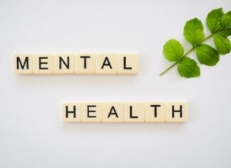 the word mental health spelled with scrabbles next to a green leaf