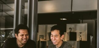 two smiling men looking at MacBook