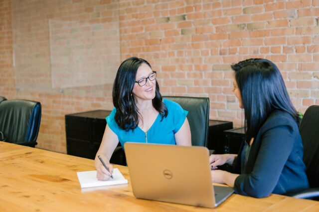 Photo by Amy Hirschi woman in teal t-shirt sitting beside woman in suit jacket