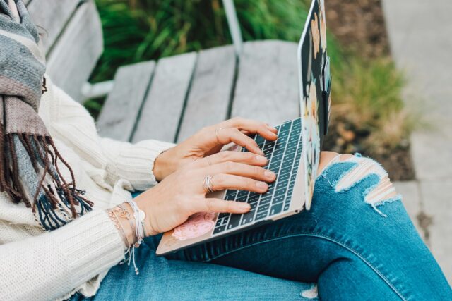 Photo by Shayna Douglas person in white long sleeve shirt and blue denim jeans using macbook pro