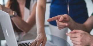 person touching and pointing MacBook Pro