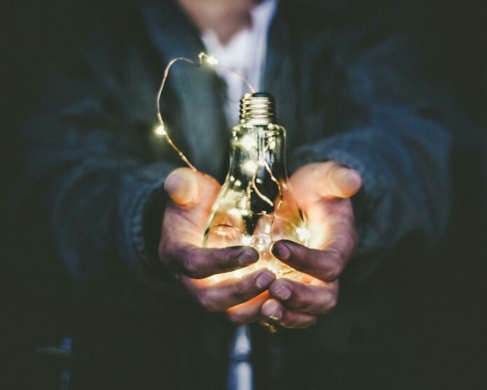 Photo by Riccardo Annandale man holding incandescent bulb