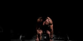 topless man in black shorts sitting on black and silver barbell