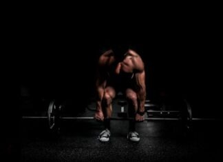The Secret Edge: Is HGH the Bodybuilder’s Best Friend? topless man in black shorts sitting on black and silver barbell