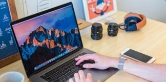 MacBook Pro turned on beside white ceramic mug
