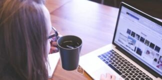 woman holding tea filled mug using MacBook
