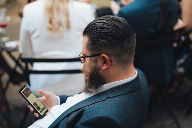 Photo by Humphrey Muleba a man sitting in a chair looking at his cell phone