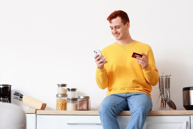 Handsome,Young,Man,With,Credit,Card,And,Mobile,Phone,Sitting