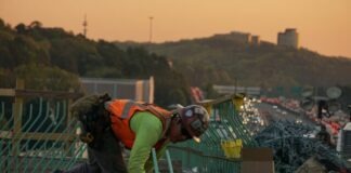 man on green galvanized iron sheet holding green bar