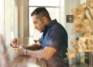 man in black button-up shirt holding smartphone