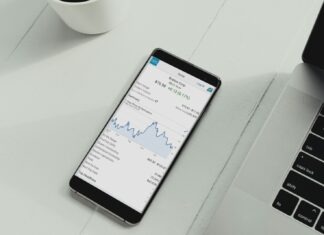 a cell phone sitting on top of a table next to a laptop