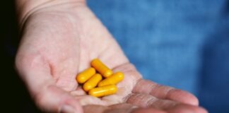 yellow medication pill on persons hand