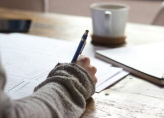Guide to Online Real Estate Classes for Beginners person writing on brown wooden table near white ceramic mug