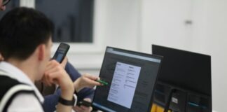A group of people sitting at a table with computers