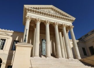 a building with columns and a clock on the front of it