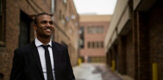smiling man standing between brown concrete buildings at daytime