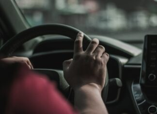 How Long Do You Have to File an Insurance Claim After a Car Accident? a person driving a car with their hand on the steering wheel