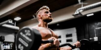 topless man in black shorts carrying black dumbbell