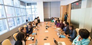 people sitting beside rectangular brown table with laptops