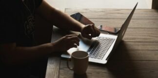 gray laptop computer on brown wooden table beside person sitting on chair