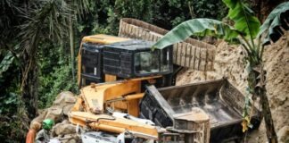two people riding motorcycle looking at the excavator accident