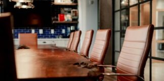 A conference room with a large wooden table and leather chairs