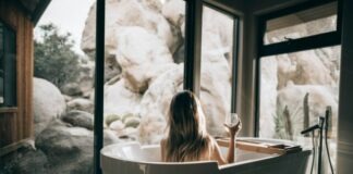 woman in white bathtub holding clear drinking glass