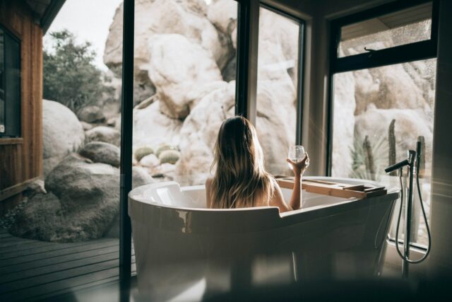 Photo by Roberto Nickson woman in white bathtub holding clear drinking glass