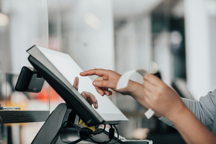 Photo by Simon Kadula a person is using a pos machine in a store
