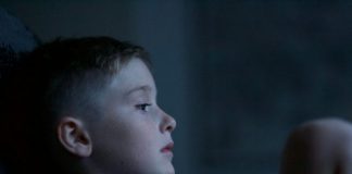 boy leaning on black wall